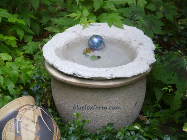 Soil  cement bird bath in place, complete with marbles for decoration